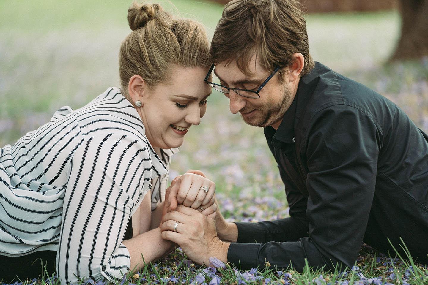 Engagement Photography - couple holding hands lying in grass