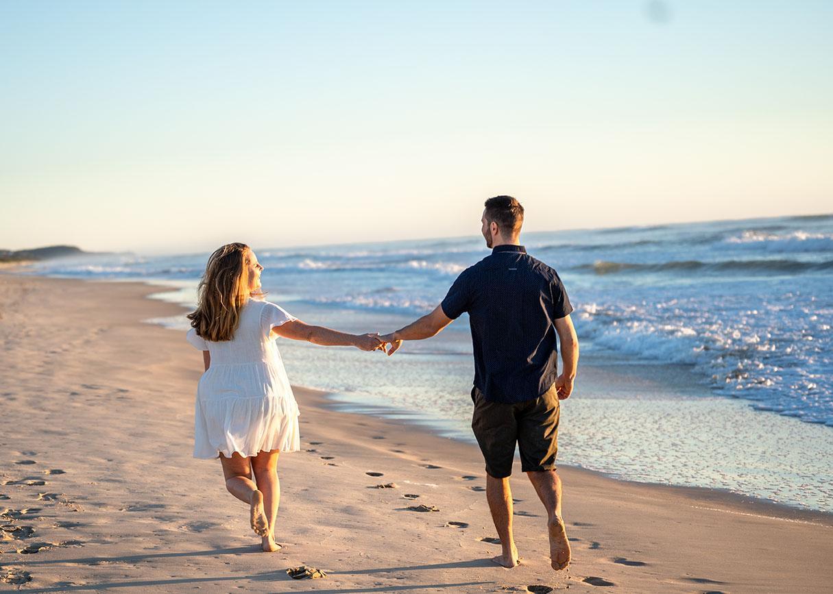 Engagement Photography couple holding hands on beach at sunset
