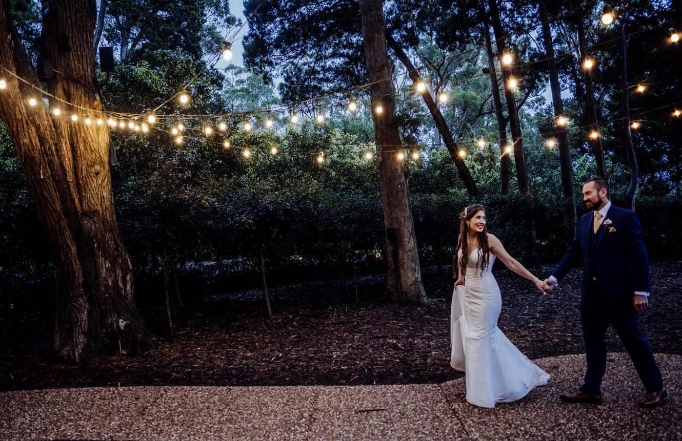 Wedding Photography Bride and Groom walking under twinkle lights