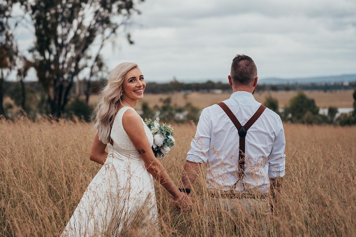 Wedding Photography - couple walking in field
