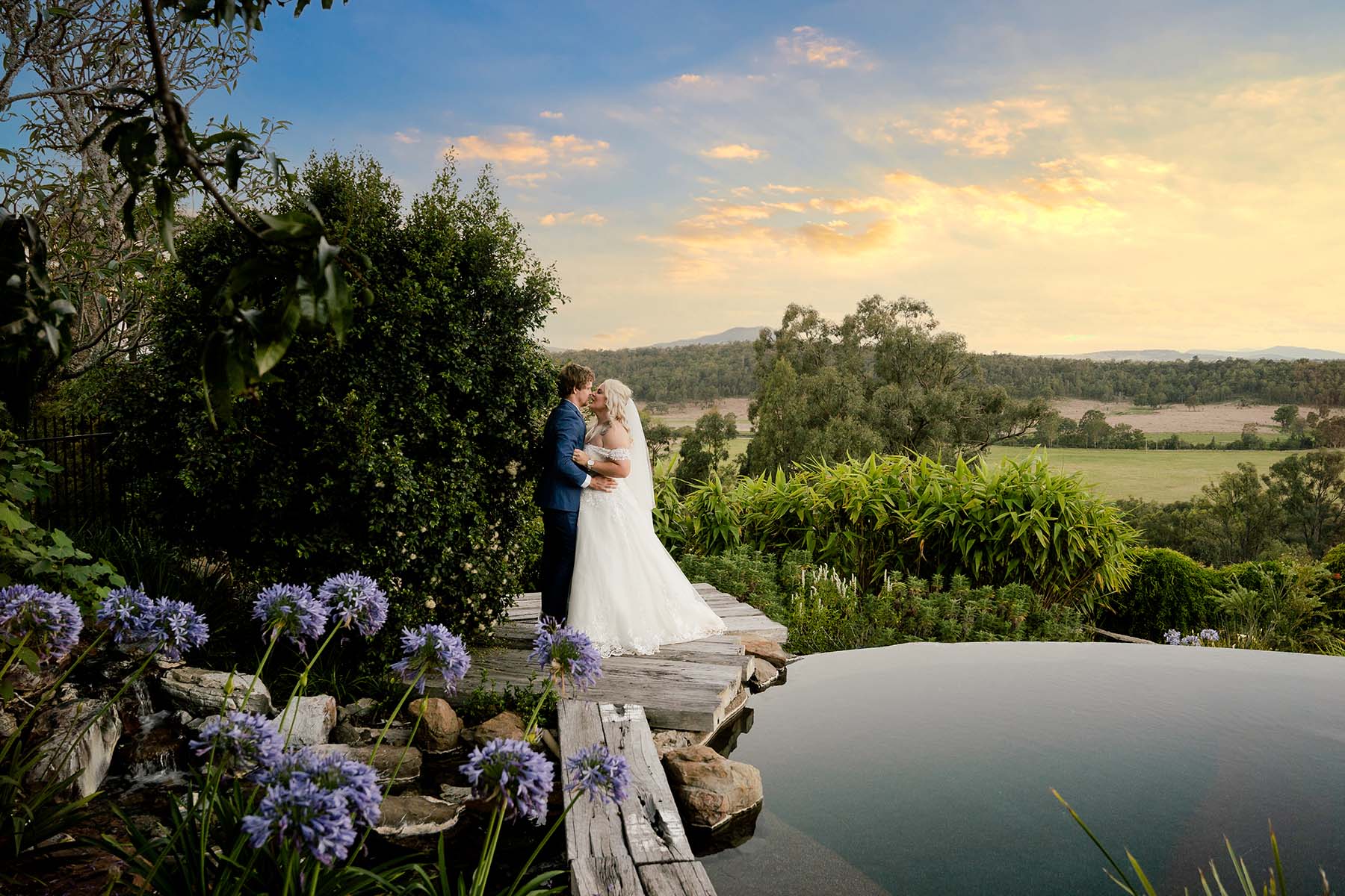 Wedding Photography - Bride and Groom embrace in front of Stunning Sunset over water