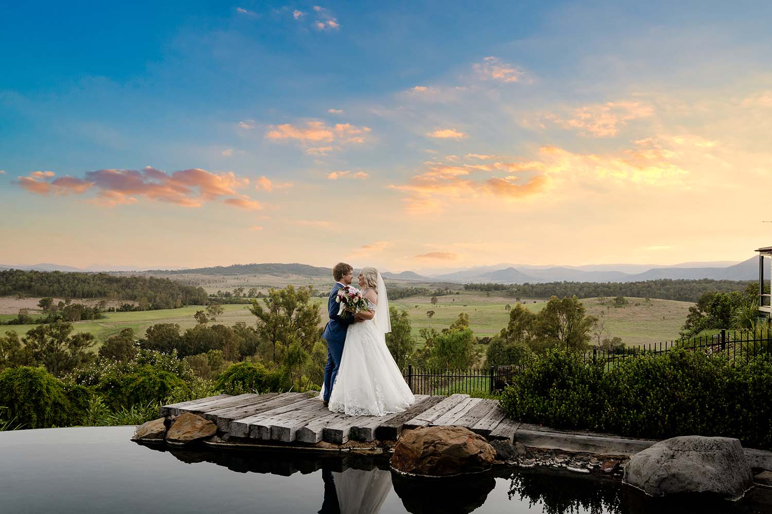 Wedding Photography - Bride and Groom embrace in front of Stunning Sunset over water
