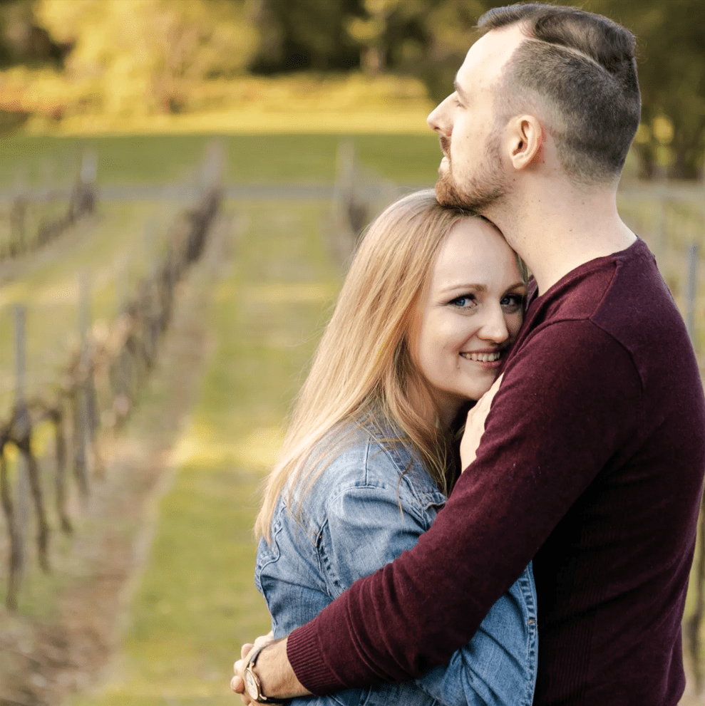 Engagement Photography - Couple embracing with vineyard in the distance