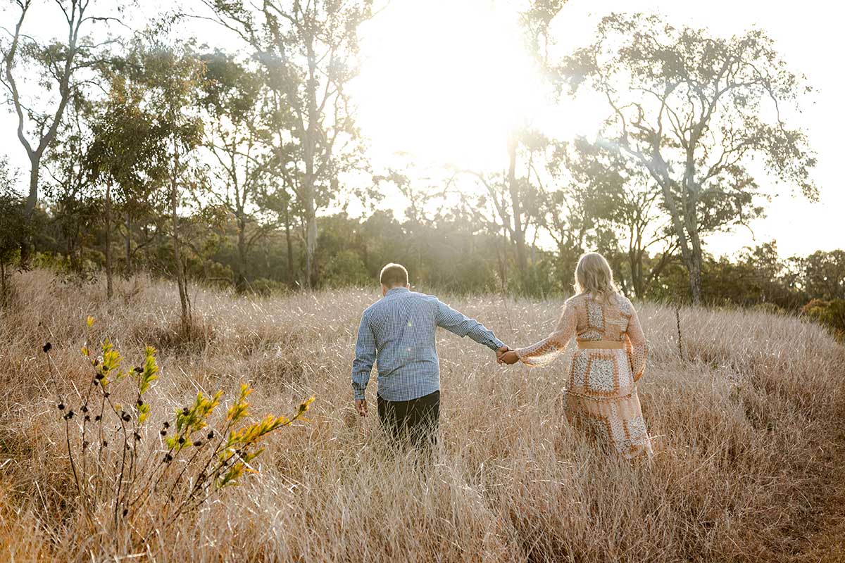 Engagement Photography - couple walking away in field