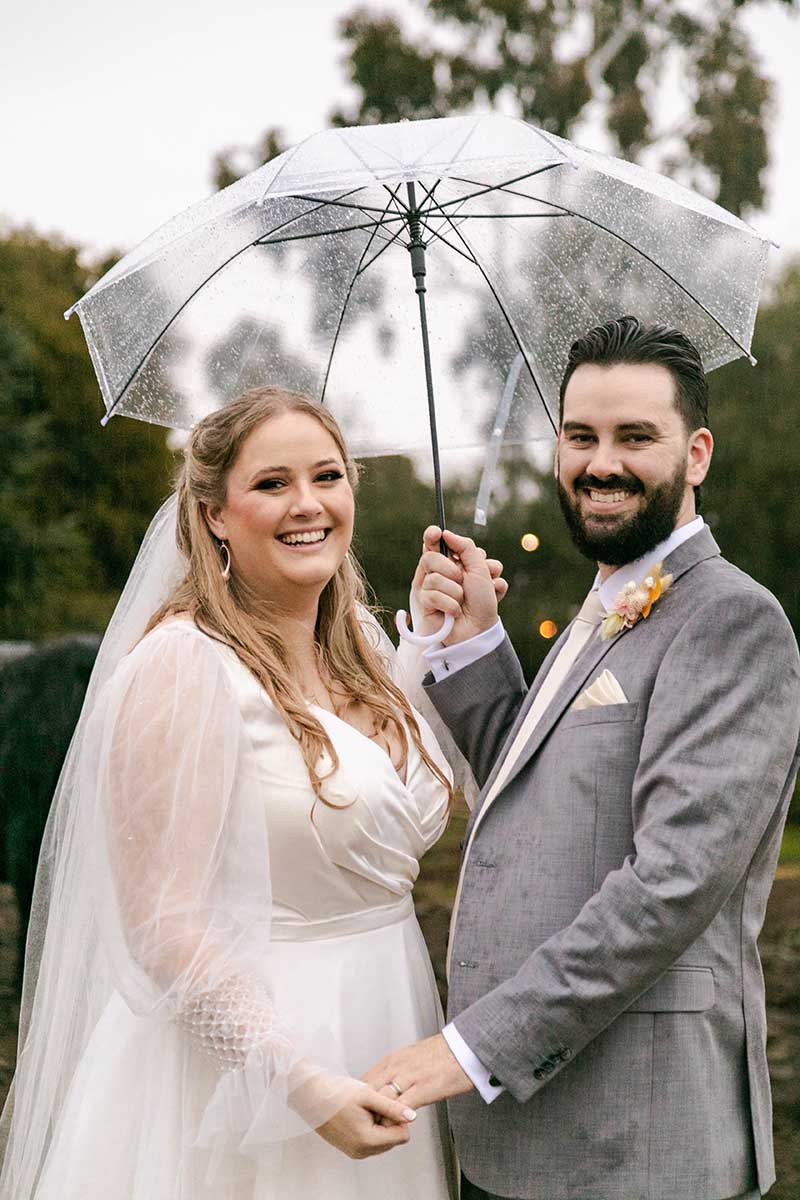 Wedding Photography - Bride and groom holding hands under umbrella