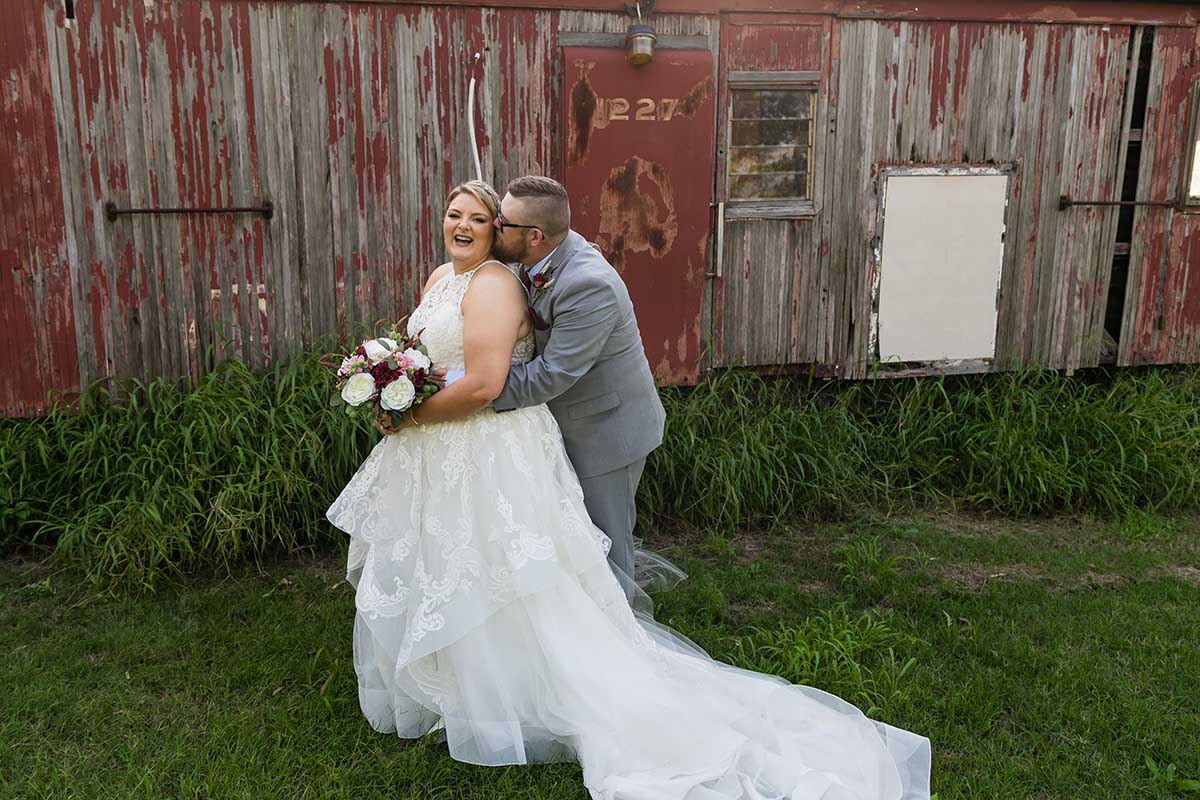 Wedding Photography - Couple embrace in front of rustic shed