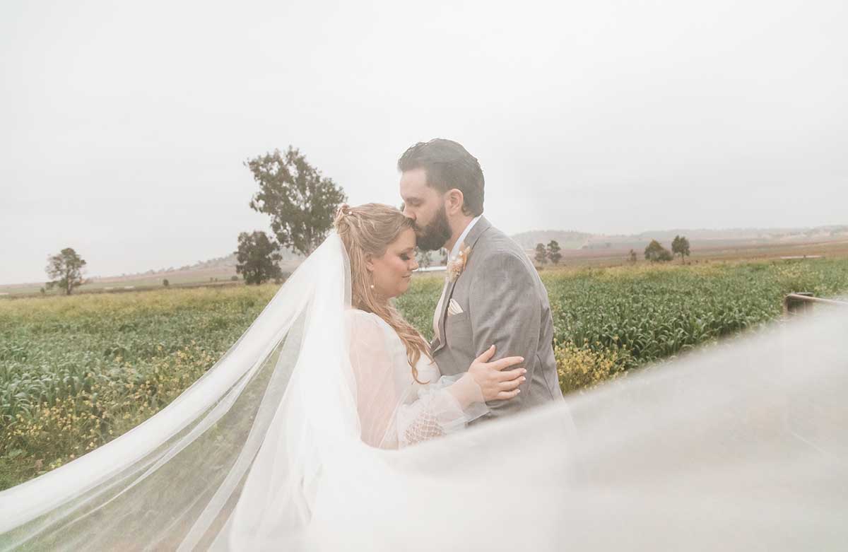 Wedding Photography - Groom kissing brides head in rain