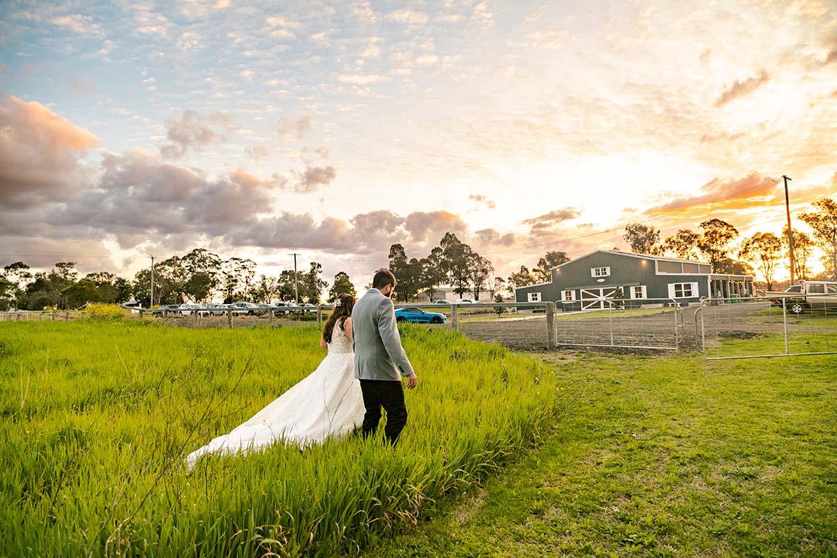 Wedding Photography - Bride and groom walking towards barn
