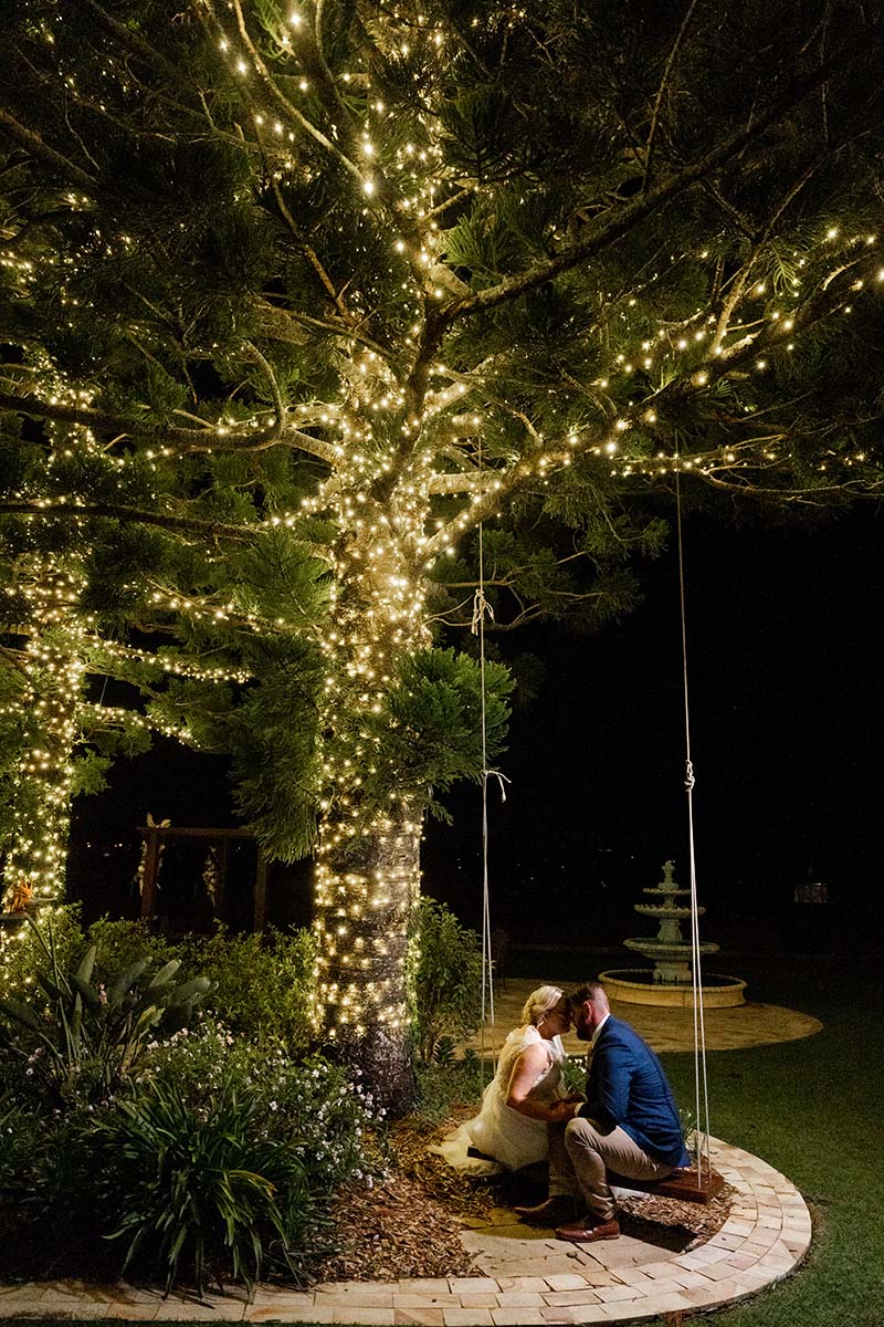 Wedding Photography – bride and groom on swing at night under lit tree