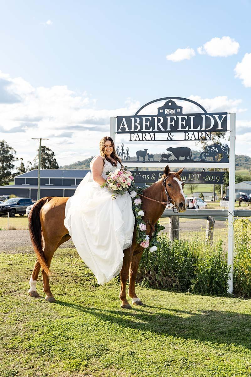 Wedding Photography - bride on horse in front of sign