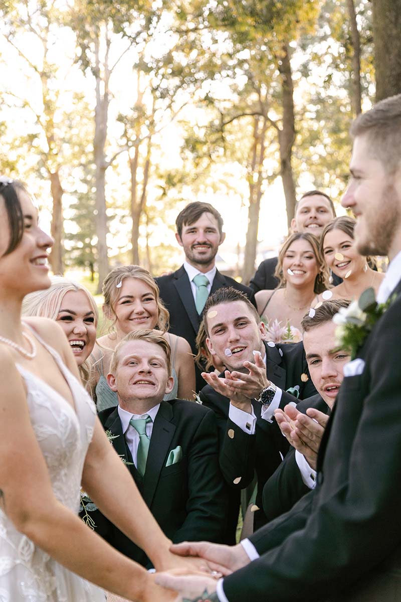 Wedding Photography - bride and groom hold hands while bridal party throws confetti