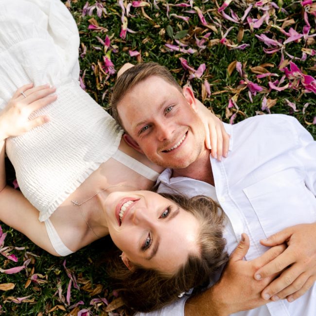 Engagement Pics Boyce Gardens - Couple laying in grass and petals