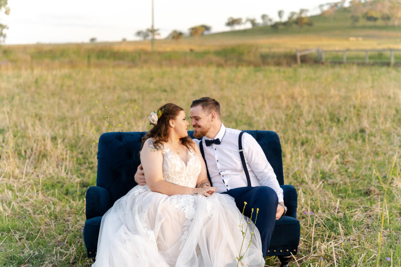Cory Kaleisha Aberfeldy Barn wedding westbrook newly wed couple sitting on a couch in a grassy field