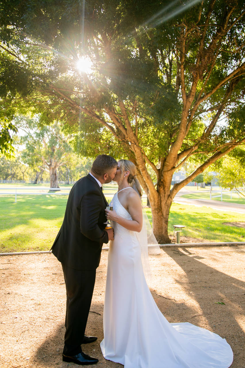 Tim and Natalia Exelby Bride and groom kiss under tree