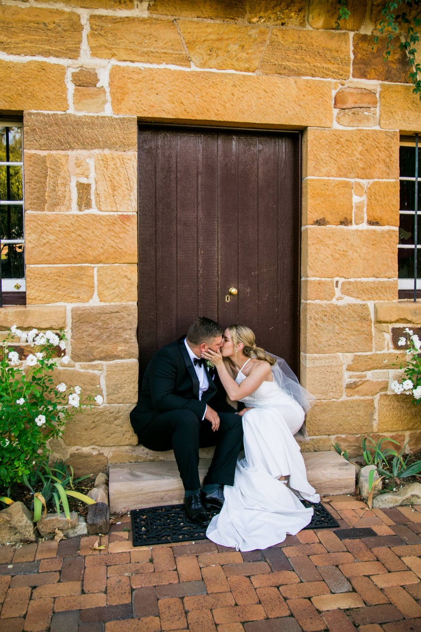Tim and Natalia Exelby Bride and groom kissing under doorway step