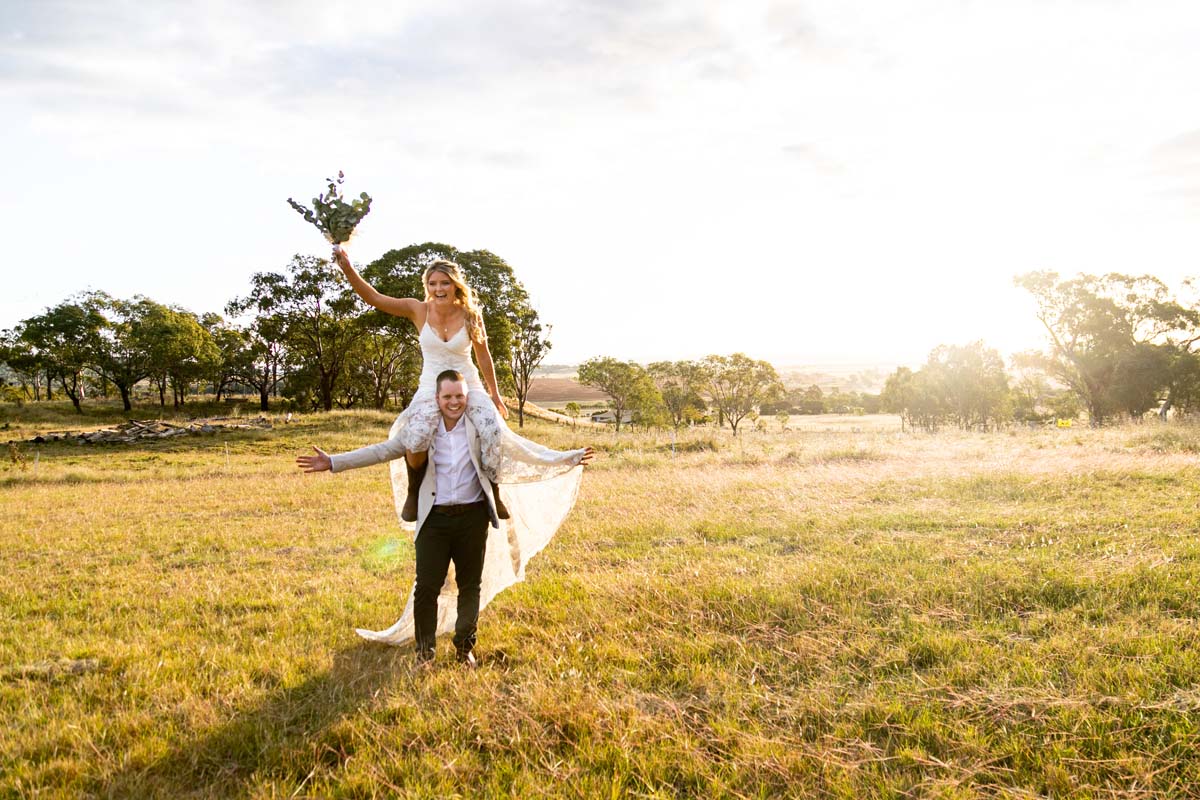 Wedding Photography bride on grooms shoulders in field