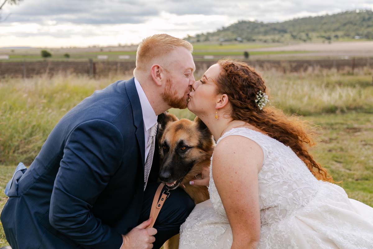 Wedding Photography couple kissing with dog squeezing in between