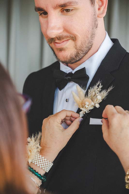 Wedding Photography groom having florals pinned to suit