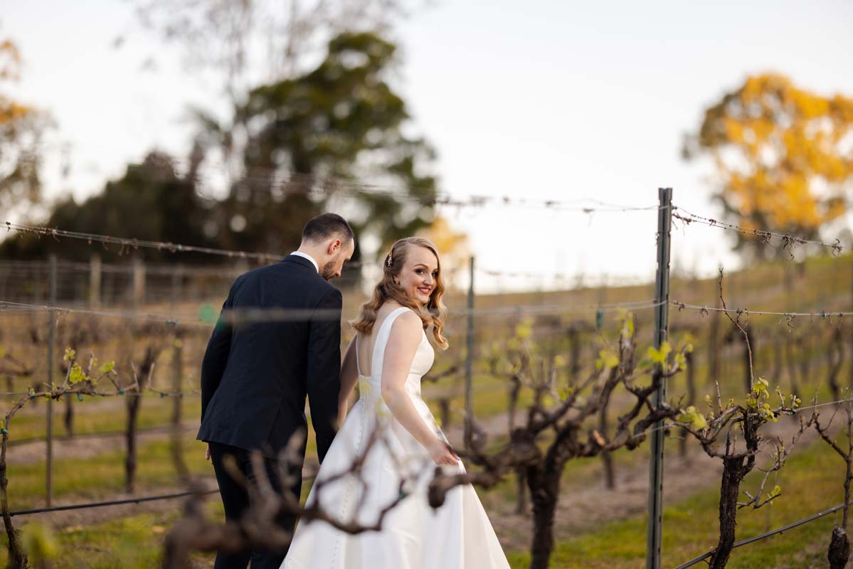 Wedding Photography bride and groom holding hands in vineyard